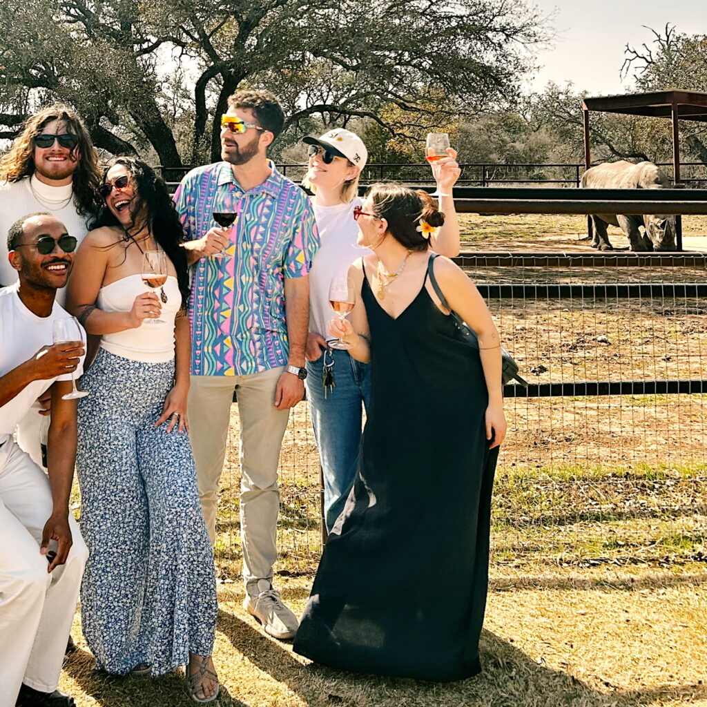 Guests in The Grove under the oaks, with the rhino habitat behind them