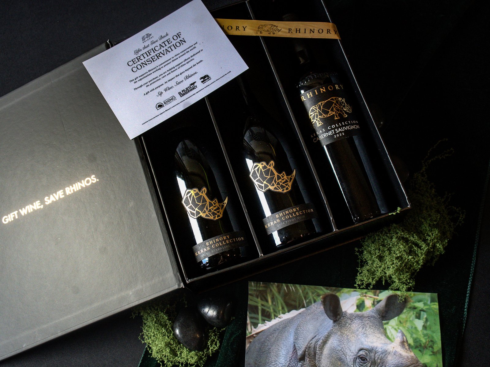 An open Rhinory gift box of three Keras Collection wines with a Certificate of Conservation, gold ribbon and a rhino photo card